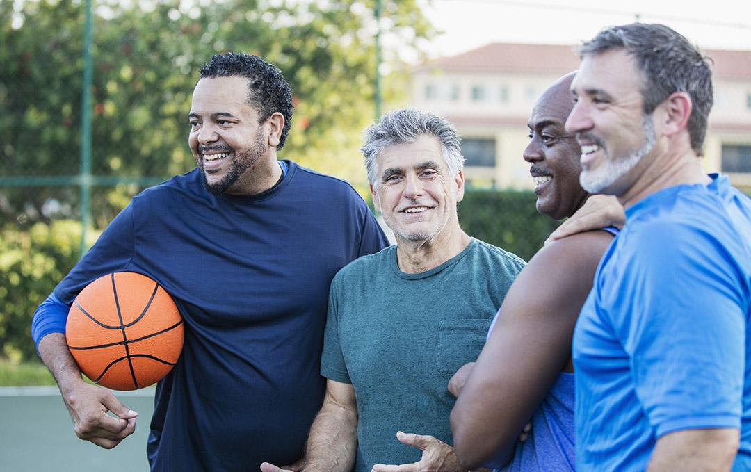 A multi-ethnic group of men enjoy the health benefits of socializing with each other on the basketball court.