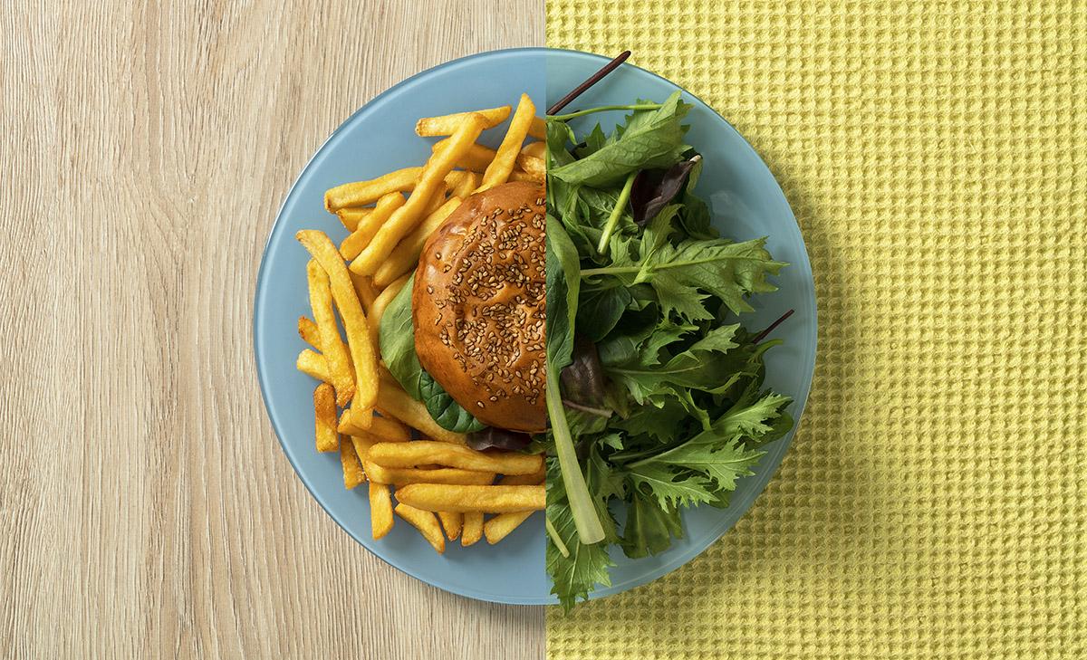 Photo of plate split in half between a burger and fries and a salad.